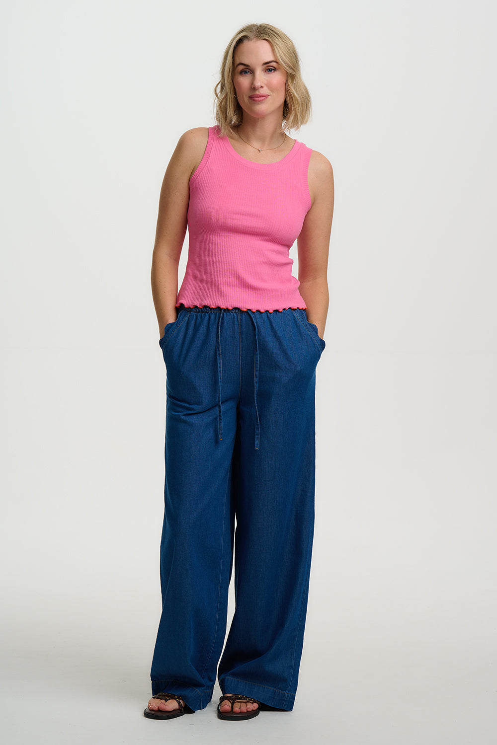 Woman wearing a pink top and blue pants on a white background