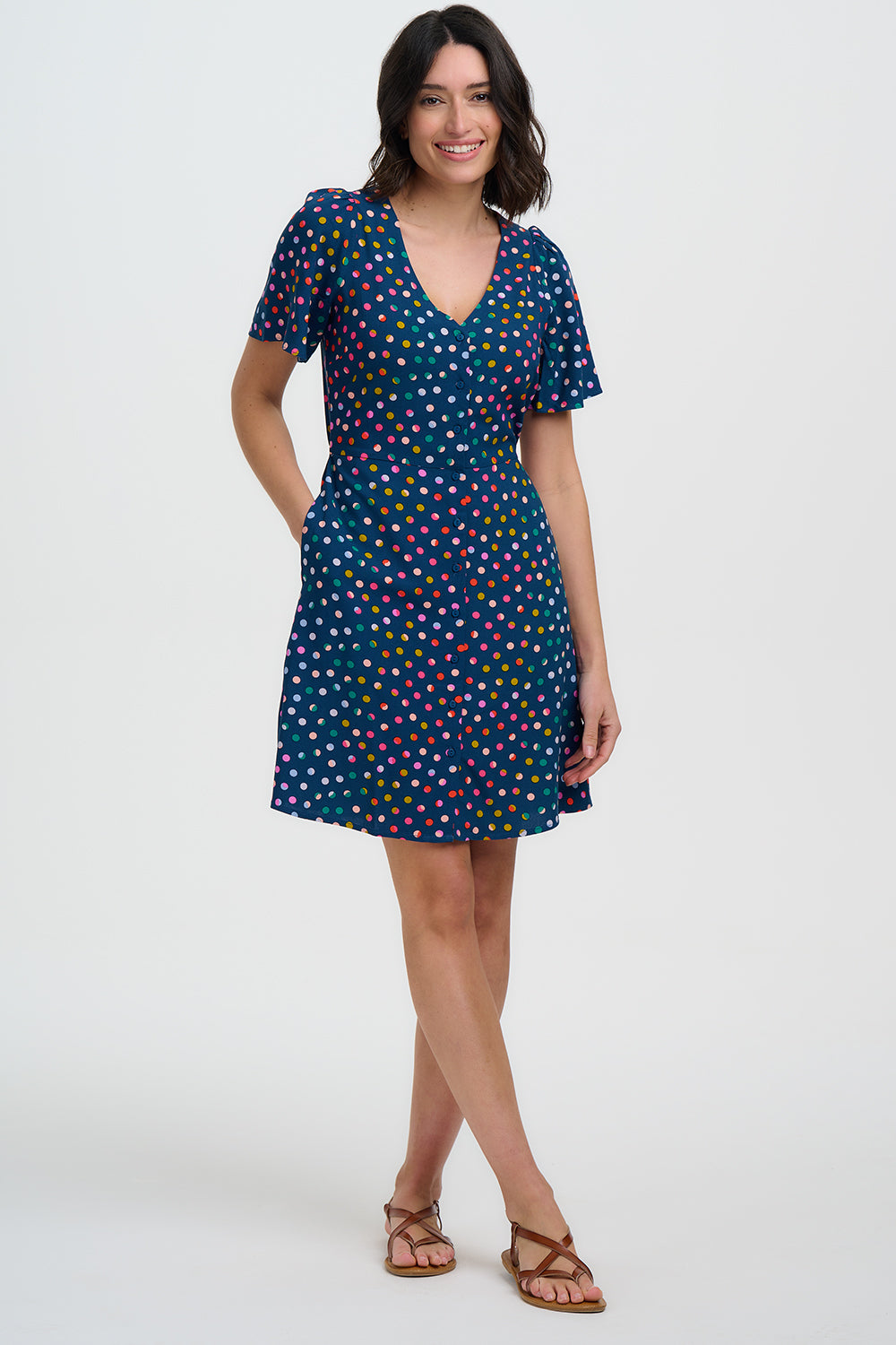 Woman wearing a blue dress with colorful polka dots on a white background