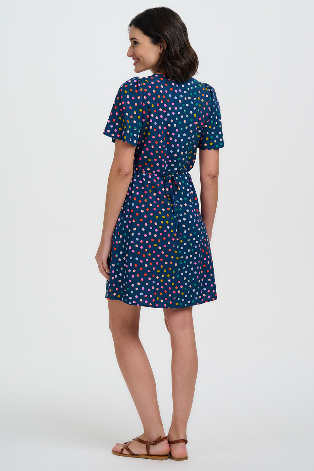 Woman wearing a blue dress with colorful polka dots on a white background