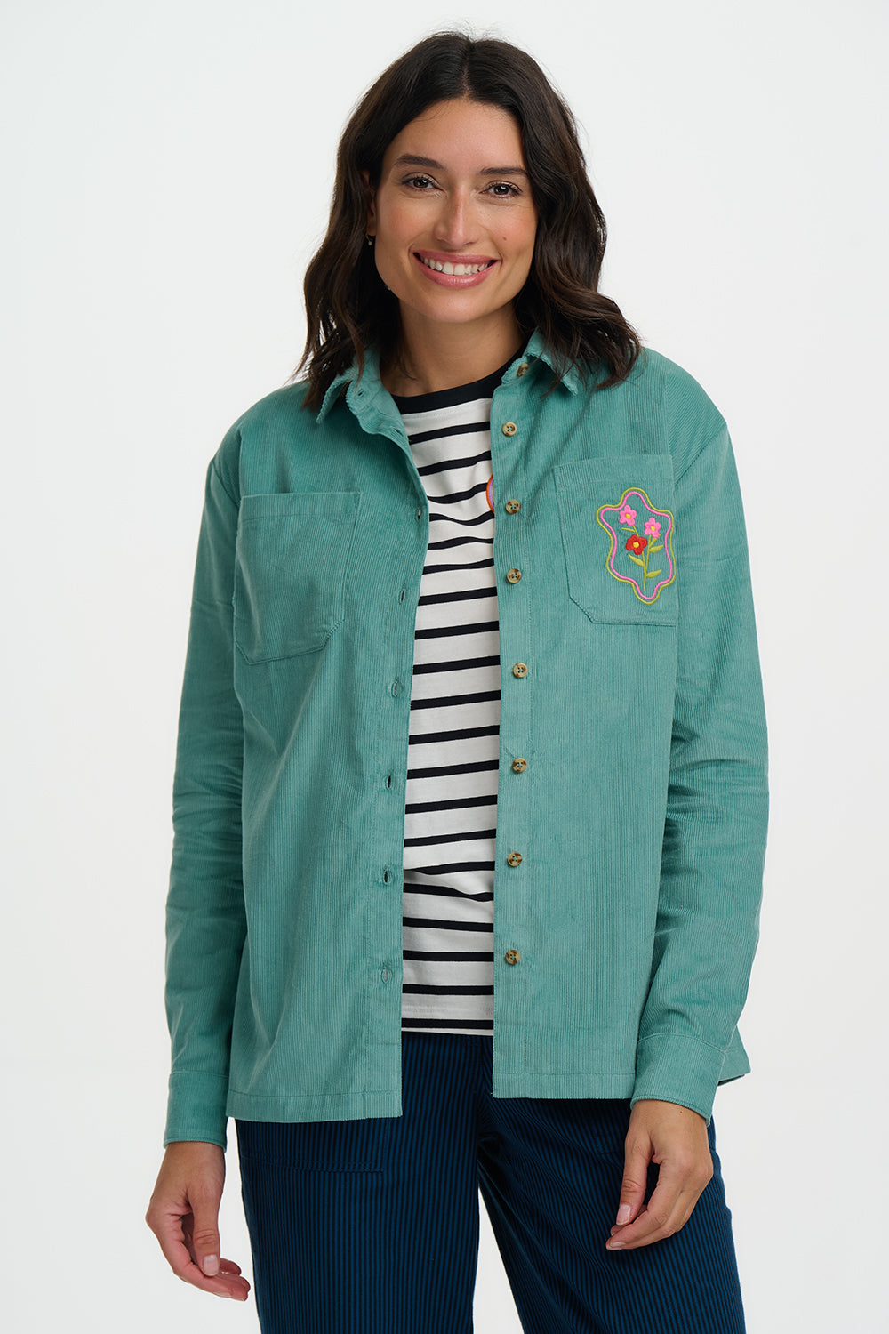 Woman wearing a teal jacket with a floral design on a white background