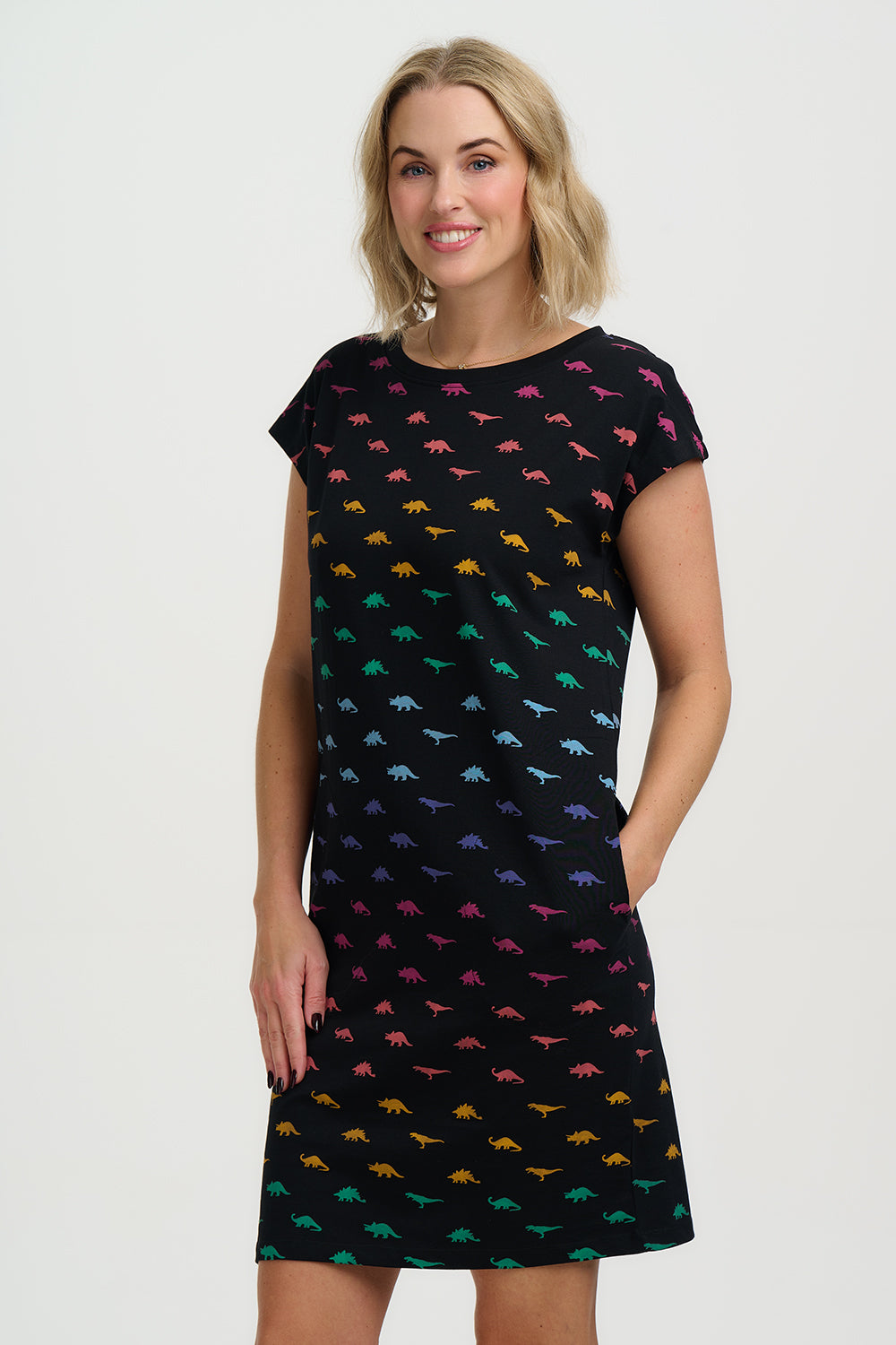 Woman wearing a black dress with colorful dinosaur pattern on a white background