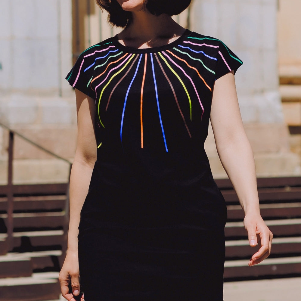 Woman wearing a black dress with colorful striped design outdoors.