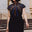 Woman wearing a black dress with colorful striped design outdoors.