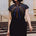 Woman wearing a black dress with colorful striped design outdoors.