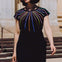 Woman wearing a black dress with colorful striped design outdoors.