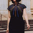 Woman wearing a black dress with colorful striped design outdoors.