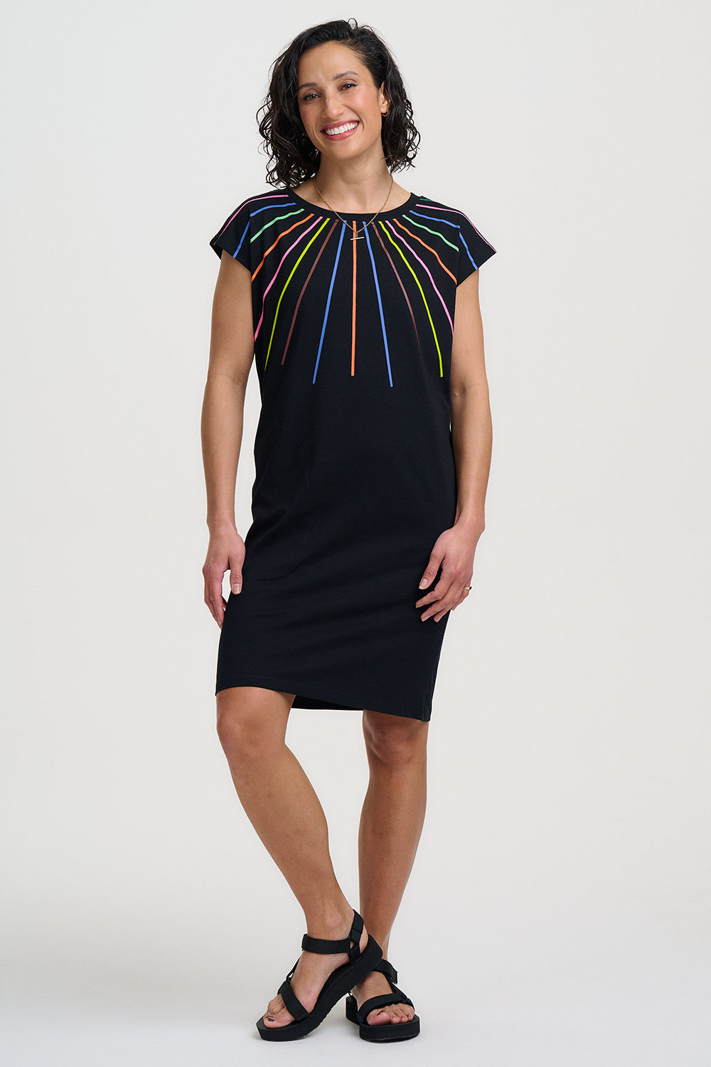 Woman wearing a black dress with colorful patterns on a white background