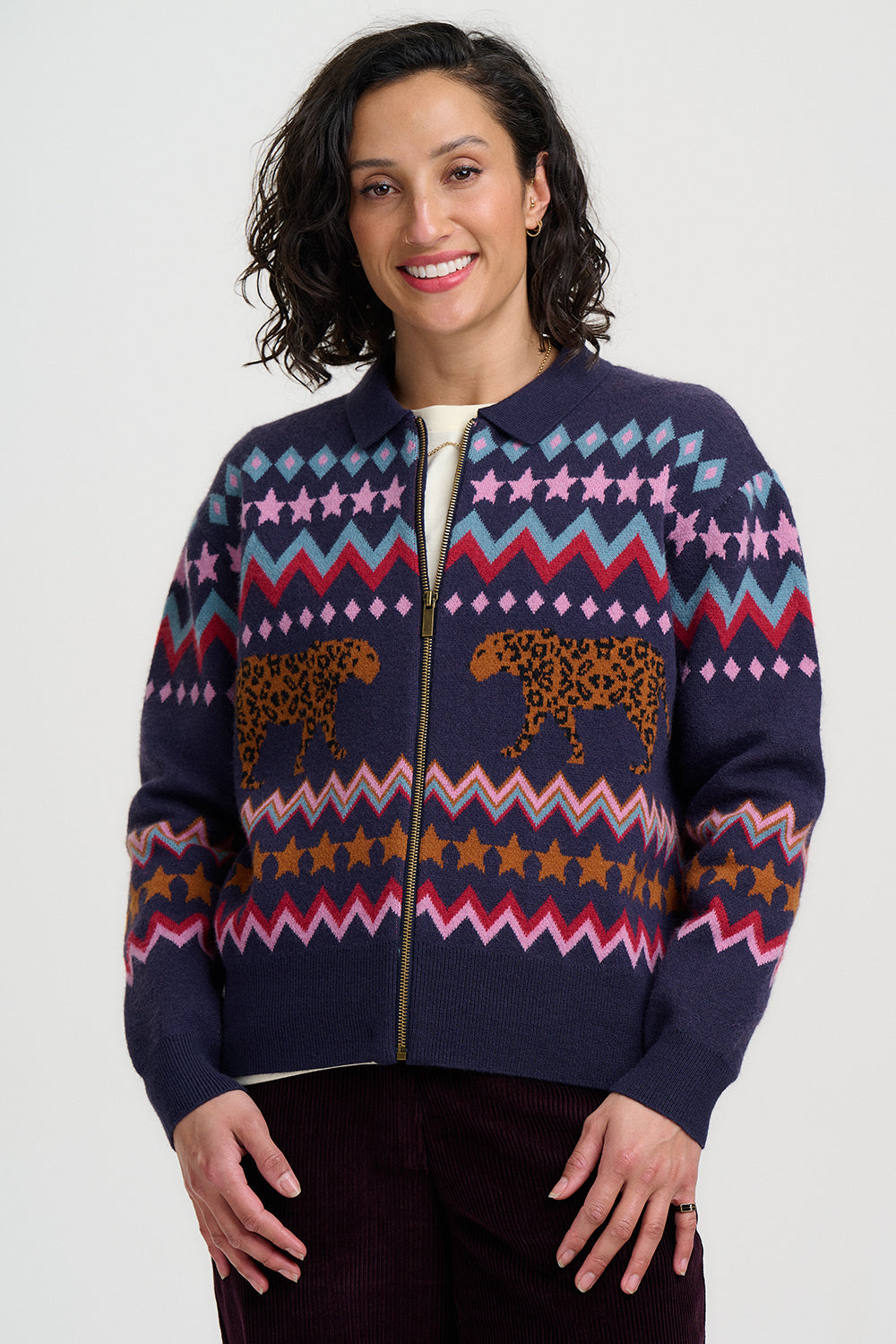 Woman wearing a navy blue zip-up sweater with colorful patterns and animal designs on a white background