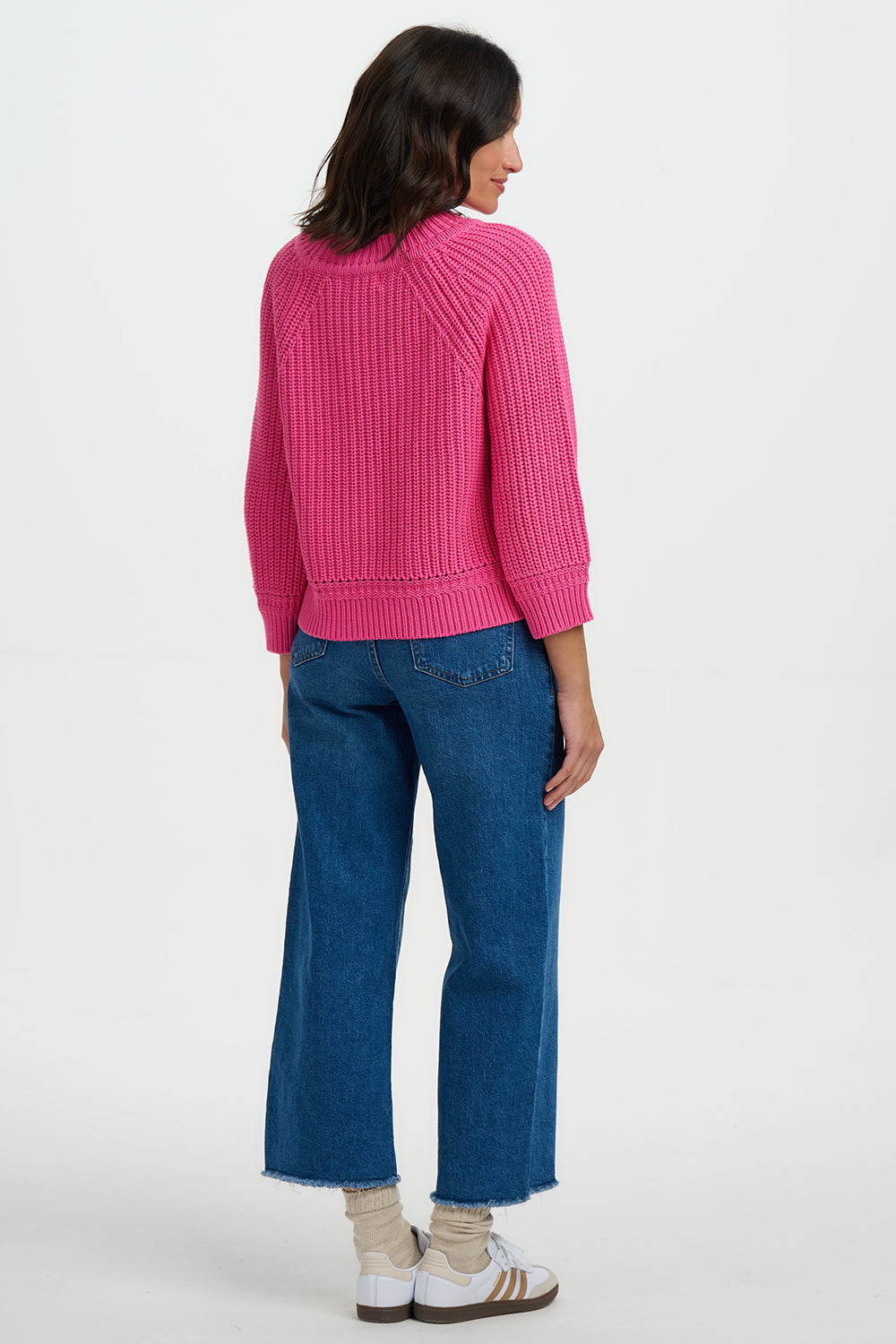Person wearing a pink sweater and blue jeans on a white background