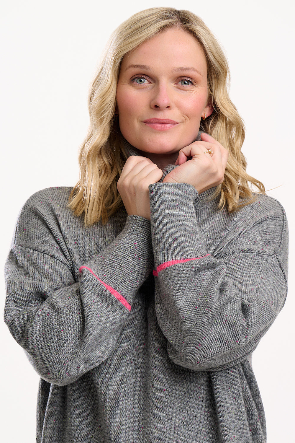 Woman wearing a gray sweater with pink accents on a white background