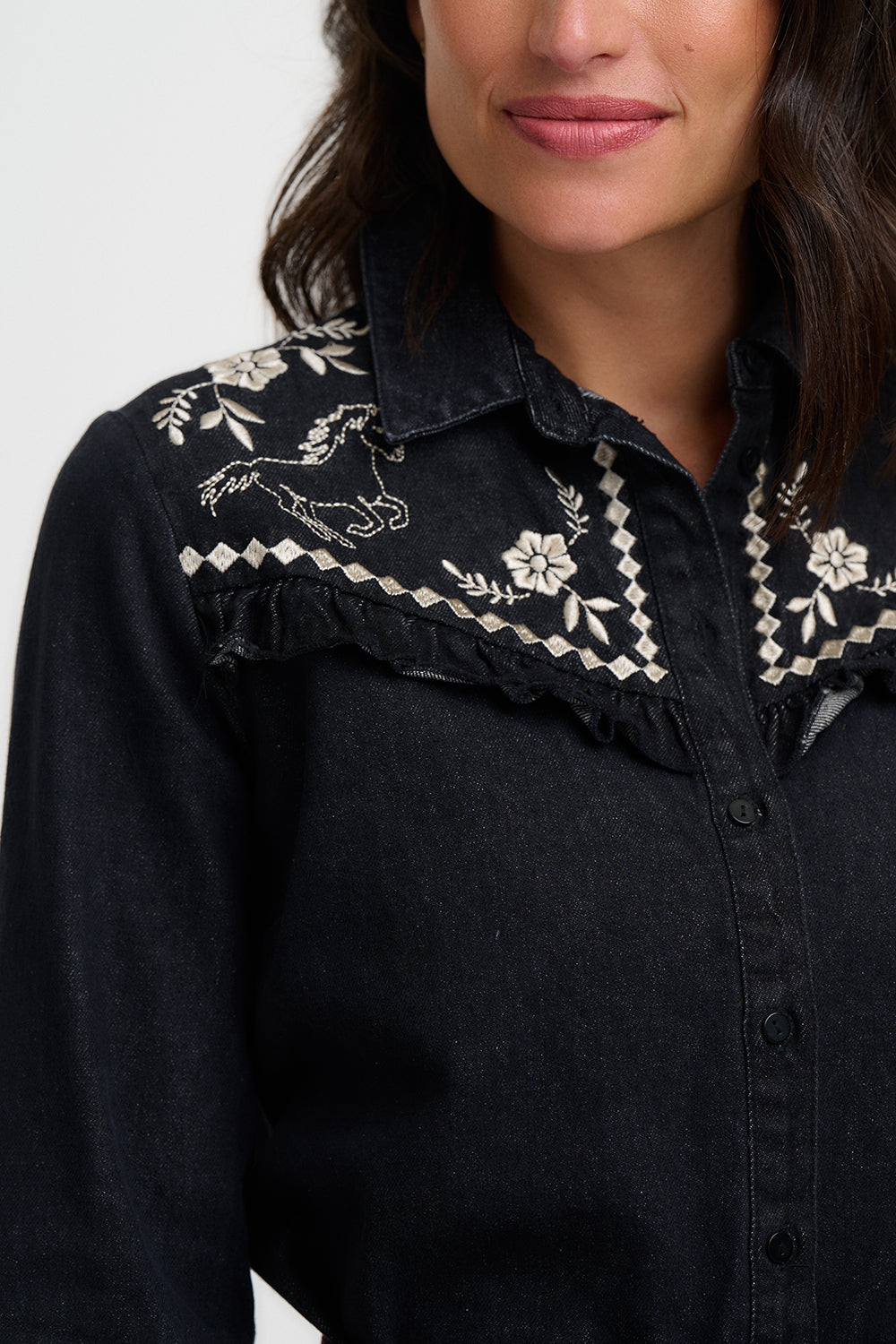 Black shirt with white embroidery on a plain background