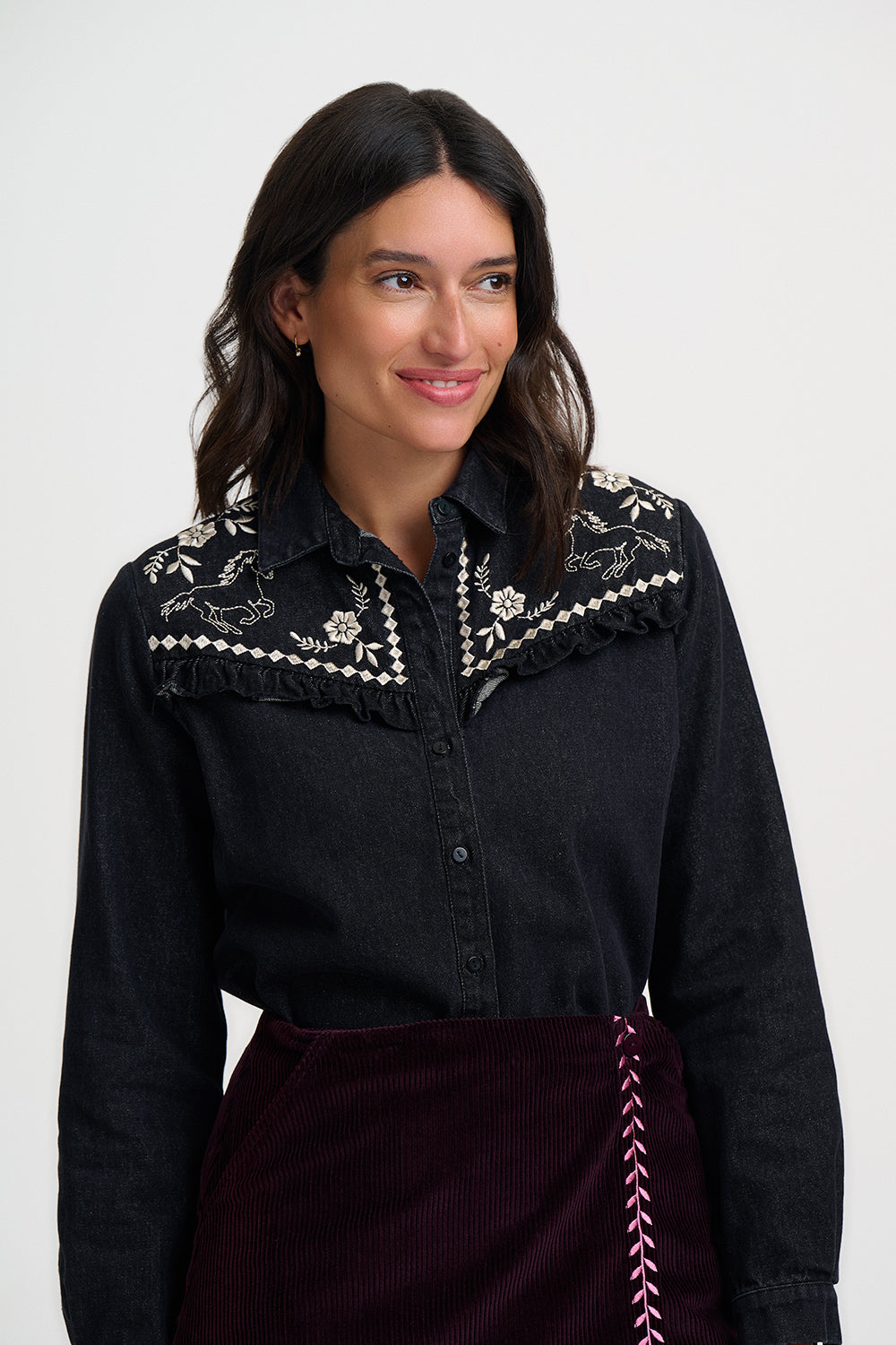 Woman wearing a black embroidered blouse with a white background