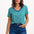 Sugarhill Brighton model wearing a green and white striped shirt with blue jeans on a white background