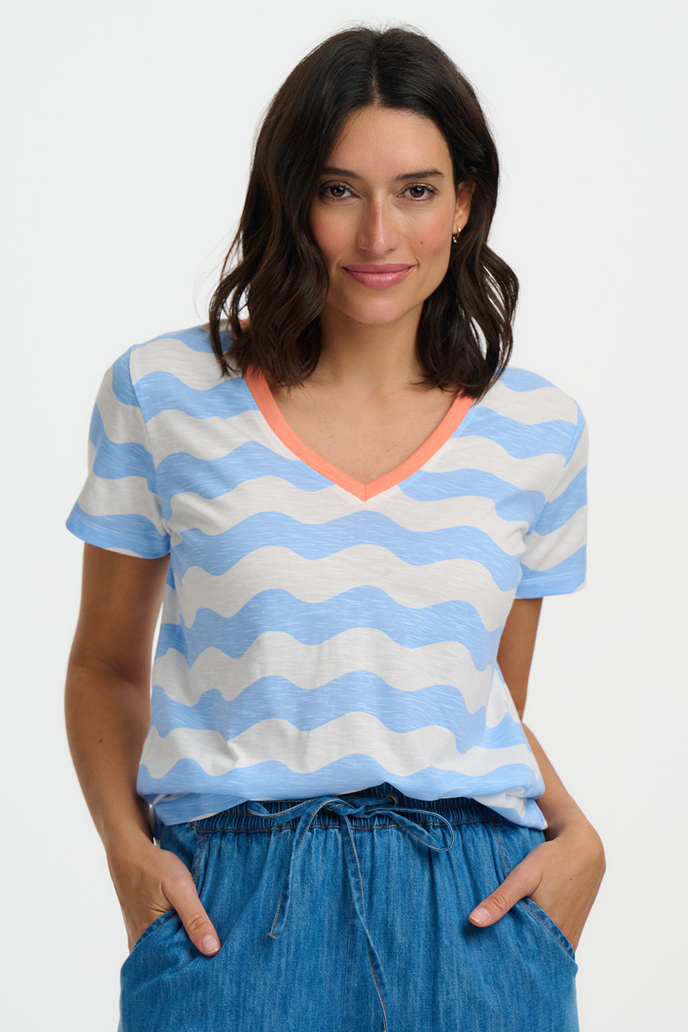 Woman wearing a blue and white striped shirt with an orange neckline on a plain background