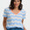 Woman wearing a blue and white striped shirt with an orange neckline on a plain background