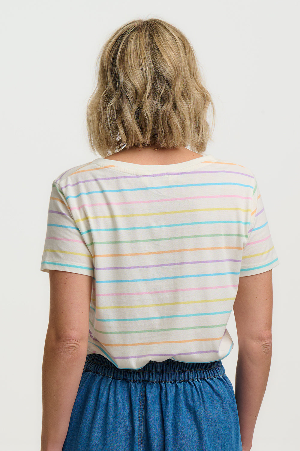 Person wearing a colorful striped shirt and blue pants on a white background