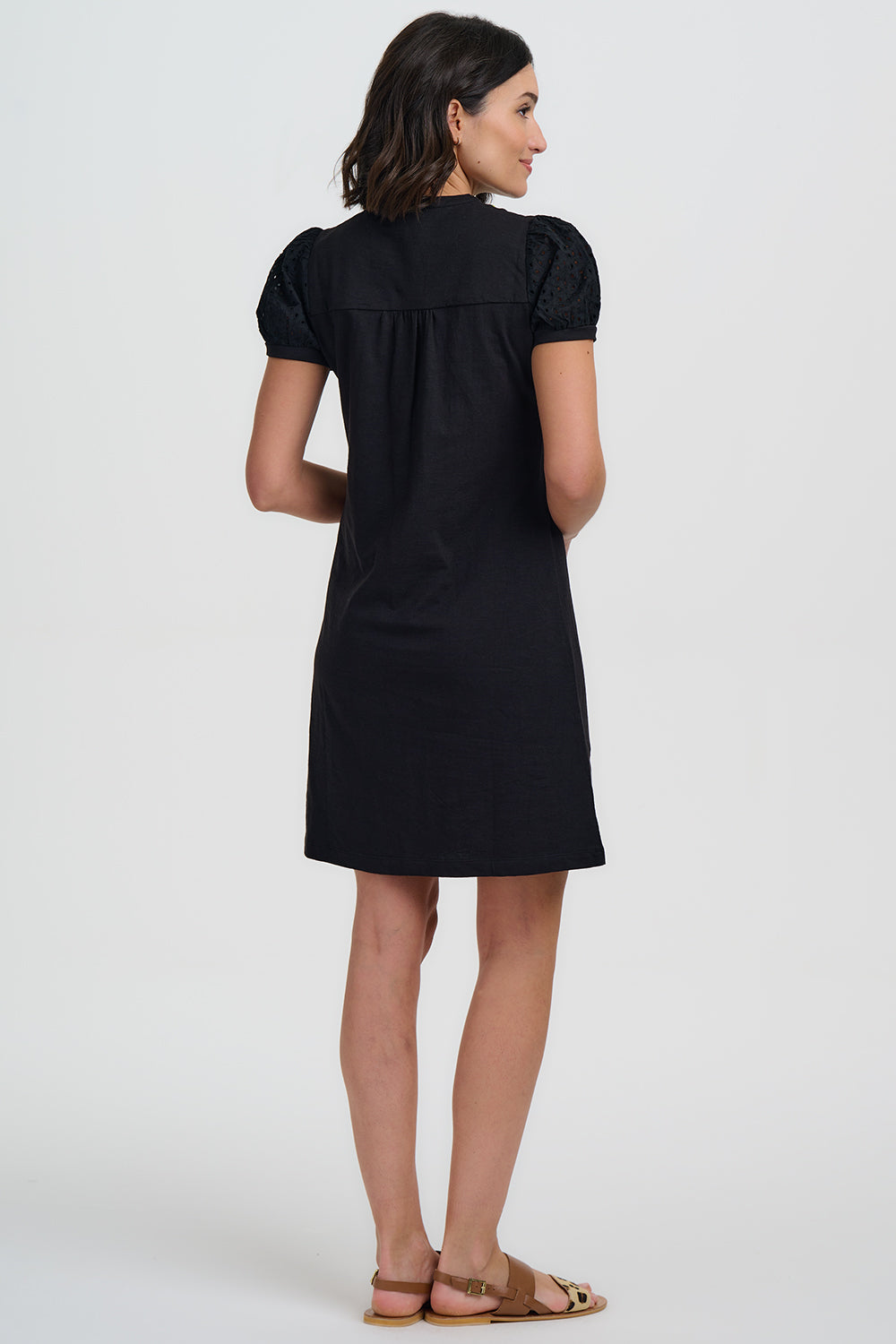 Woman wearing a black dress with puff sleeves on a white background