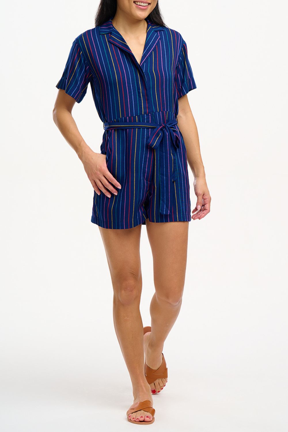 A navy playsuit with thin rainbow stripes, featuring a V-neck shirt collar, button-down front, and a tie belt.
