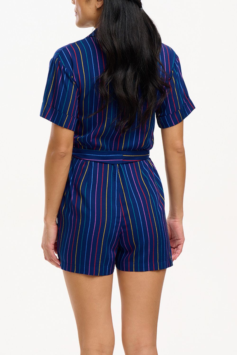 A navy playsuit with thin rainbow stripes, featuring a V-neck shirt collar, button-down front, and a tie belt.