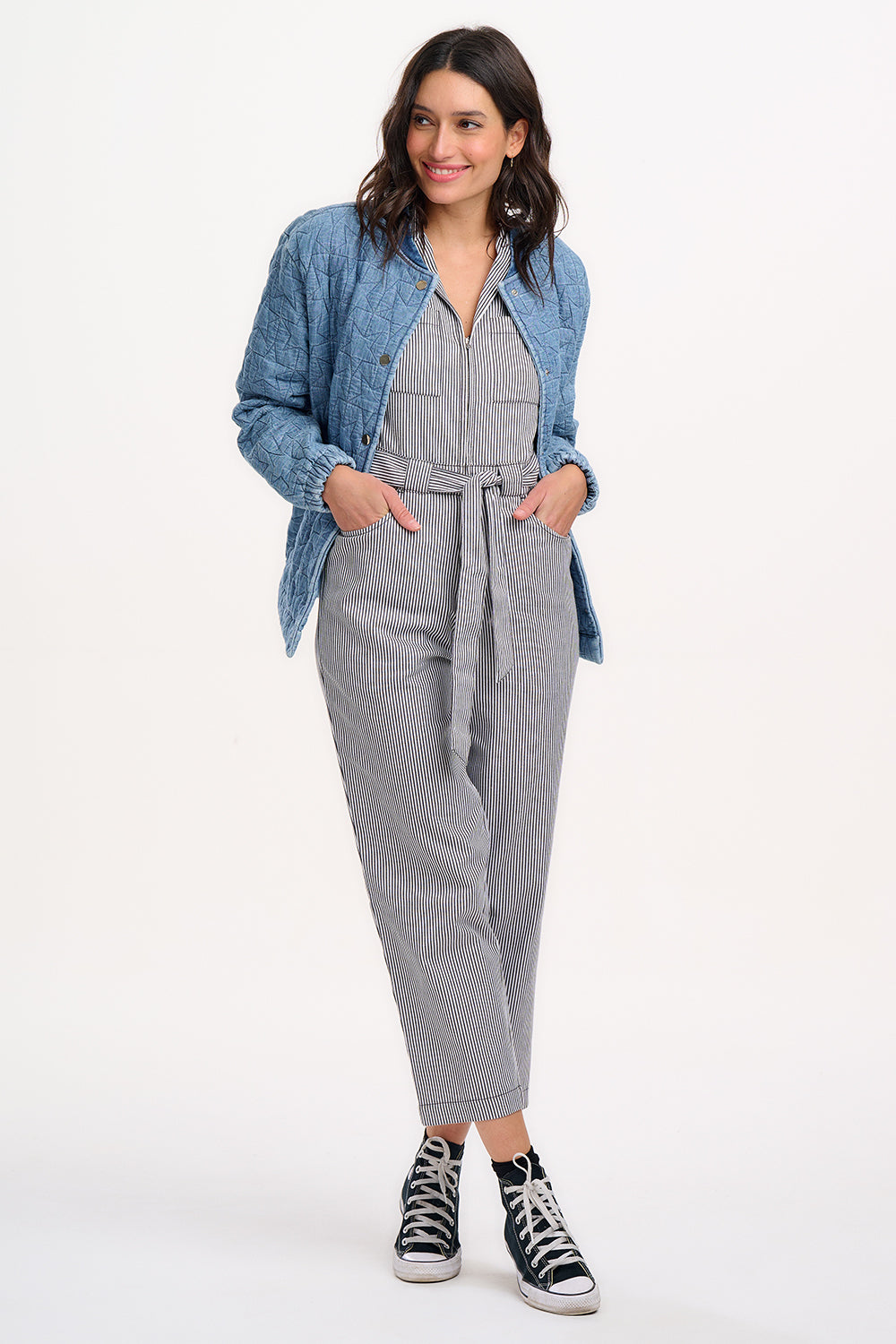 A woman wearing a light blue denim quilted bomber jacket with star quilt pattern, featuring a crew neck, popper front fastening, and elasticated back hem and cuffs.