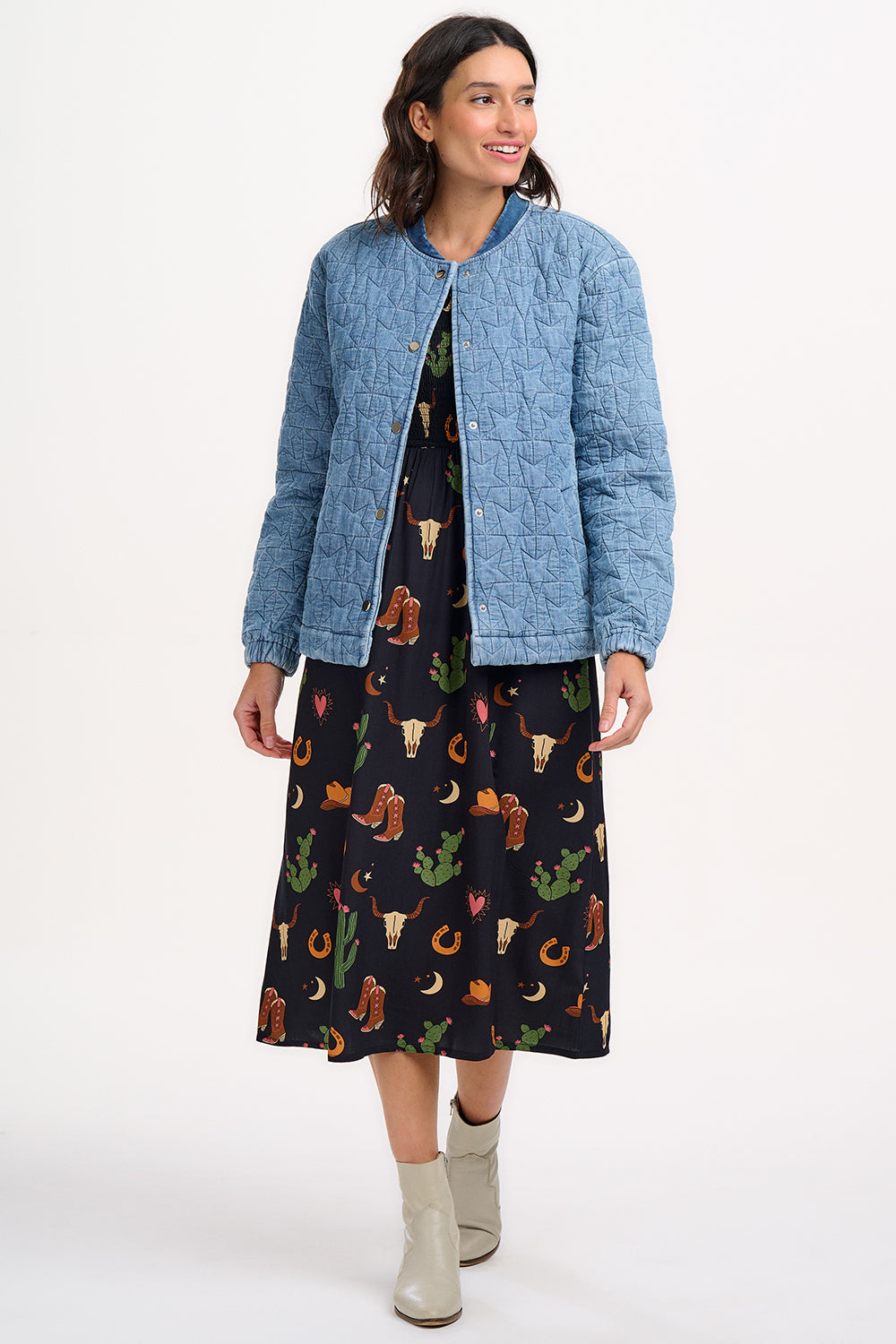 A woman wearing a light blue denim quilted bomber jacket with star quilt pattern, featuring a crew neck, popper front fastening, and elasticated back hem and cuffs.