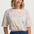 Woman wearing a colorful patterned shirt with blue pants on a white background