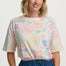 Woman wearing a colorful patterned shirt with blue pants on a white background