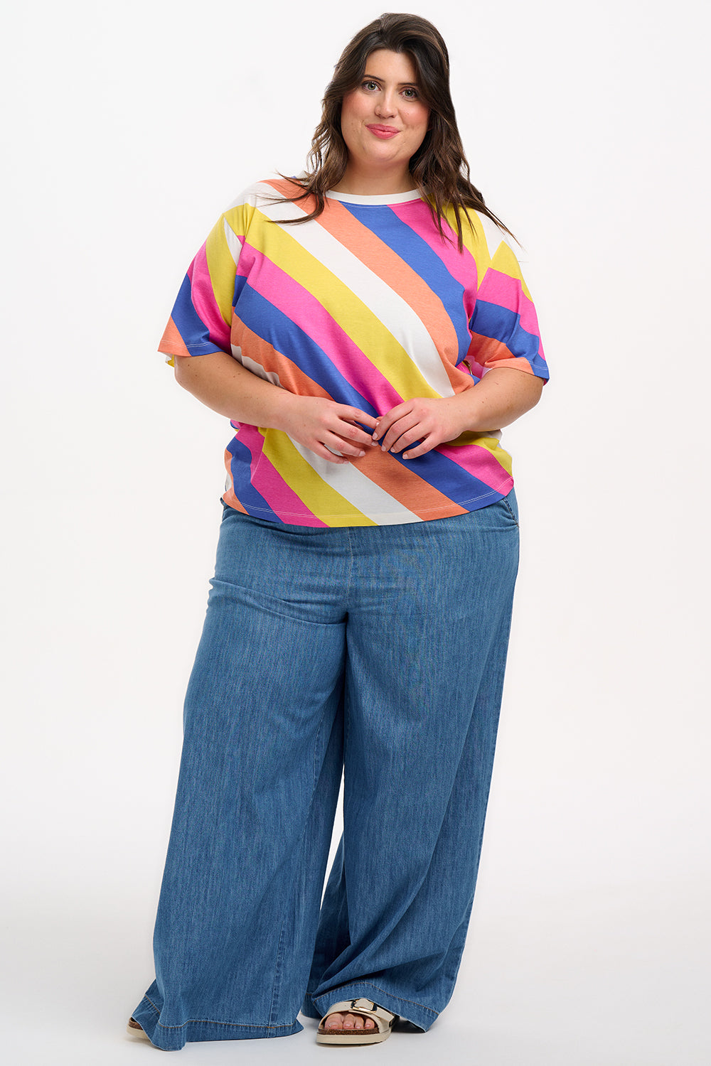 A model wearing a multicolored striped relaxed fit t-shirt with short sleeves and a round neckline.