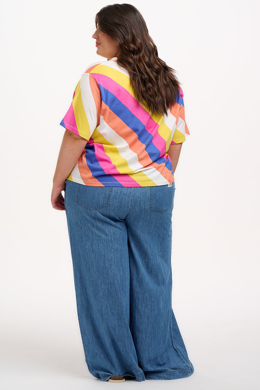 A model wearing a multicolored striped relaxed fit t-shirt with short sleeves and a round neckline.