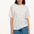 A woman modeling an oversized white t-shirt with a colorful sprinkle print, paired with denim shorts.