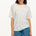 A woman modeling an oversized white t-shirt with a colorful sprinkle print, paired with denim shorts.