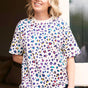 A woman wearing an oversized white t-shirt with a multicolored leopard print pattern, paired with blue jeans.