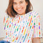 A person wearing an off-white relaxed fit t-shirt with a bold broken lines print in vibrant colors.