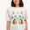 A woman smiling and wearing an off-white colored t-shirt with a mirrored jungle print design, featuring palm trees, leopards, and flowers.