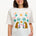 A woman smiling and wearing an off-white colored t-shirt with a mirrored jungle print design, featuring palm trees, leopards, and flowers.