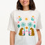 A woman smiling and wearing an off-white colored t-shirt with a mirrored jungle print design, featuring palm trees, leopards, and flowers.