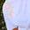 White t-shirt with yellow embroidered designs on a blurred natural background