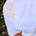 White t-shirt with yellow embroidered designs on a blurred natural background