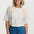 Woman wearing a white t-shirt with floral embroidery and blue pants on a white background