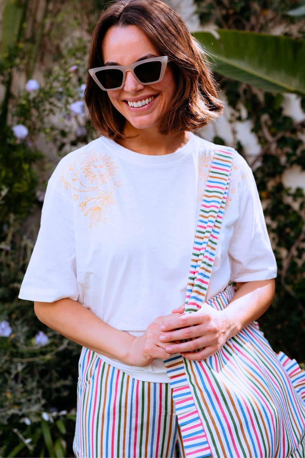 Woman wearing a white t-shirt and colorful striped pants outdoors