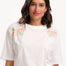 Sugarhill Brighton model wearing a white t-shirt with floral designs on a plain background
