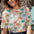 A woman smiling and wearing a relaxed fit t-shirt with a colorful palm tree print.
