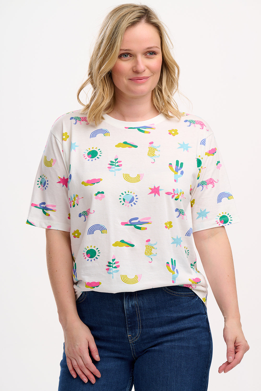 A woman wearing an oversized white t-shirt with a colorful animal and floral print, paired with blue jeans.