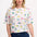 A woman wearing an oversized white t-shirt with a colorful animal and floral print, paired with blue jeans.