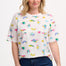 A woman wearing an oversized white t-shirt with a colorful animal and floral print, paired with blue jeans.