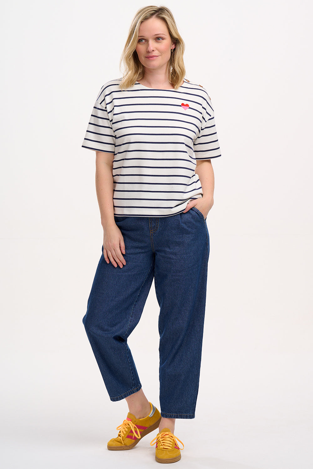 A woman wearing an off-white and navy striped short-sleeved t-shirt with a small embroidered red and pink heart on the chest.