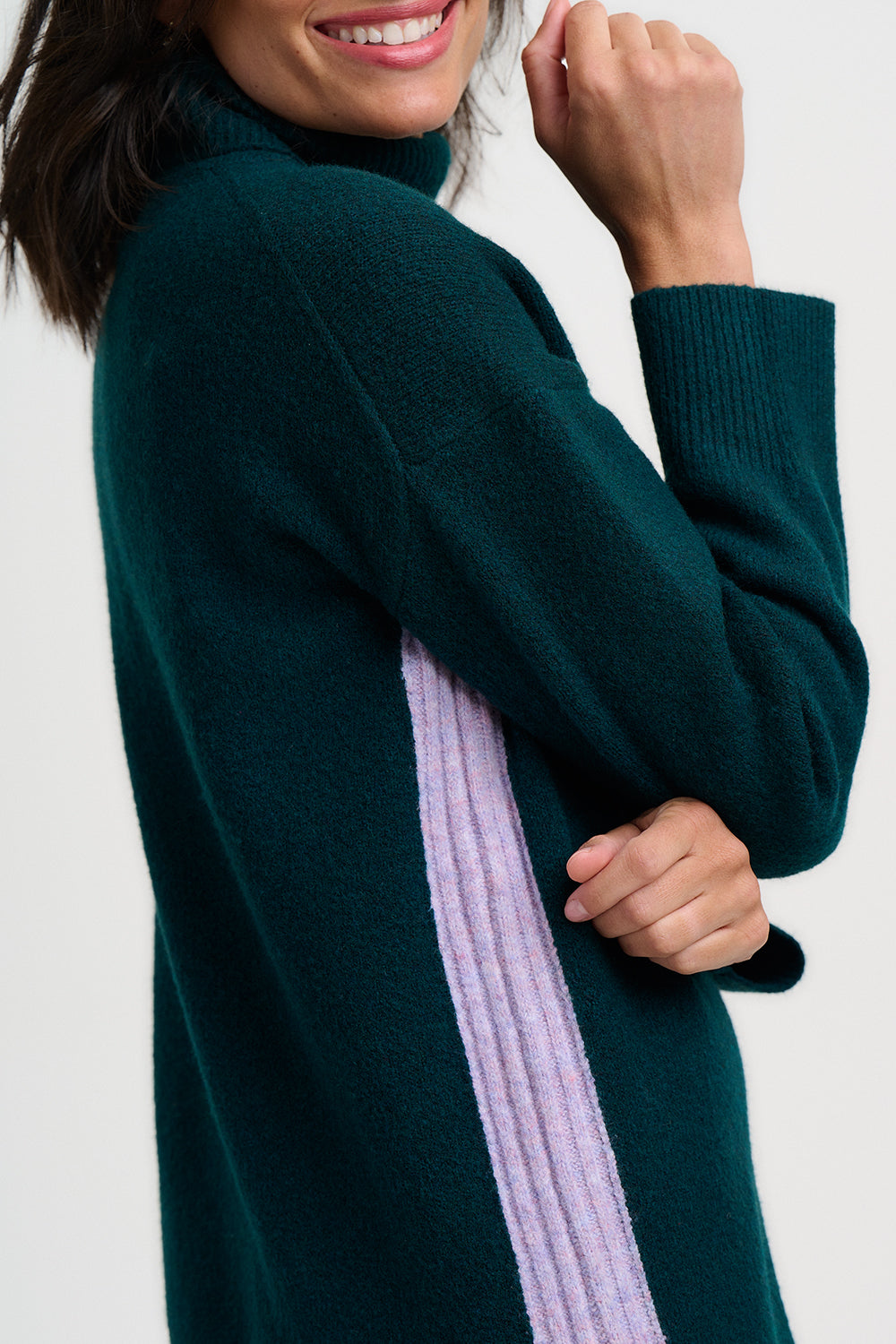 Woman wearing a dark green sweater with a light purple stripe on a white background