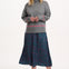 Woman wearing a gray sweater with pink trim and a patterned skirt on a white background