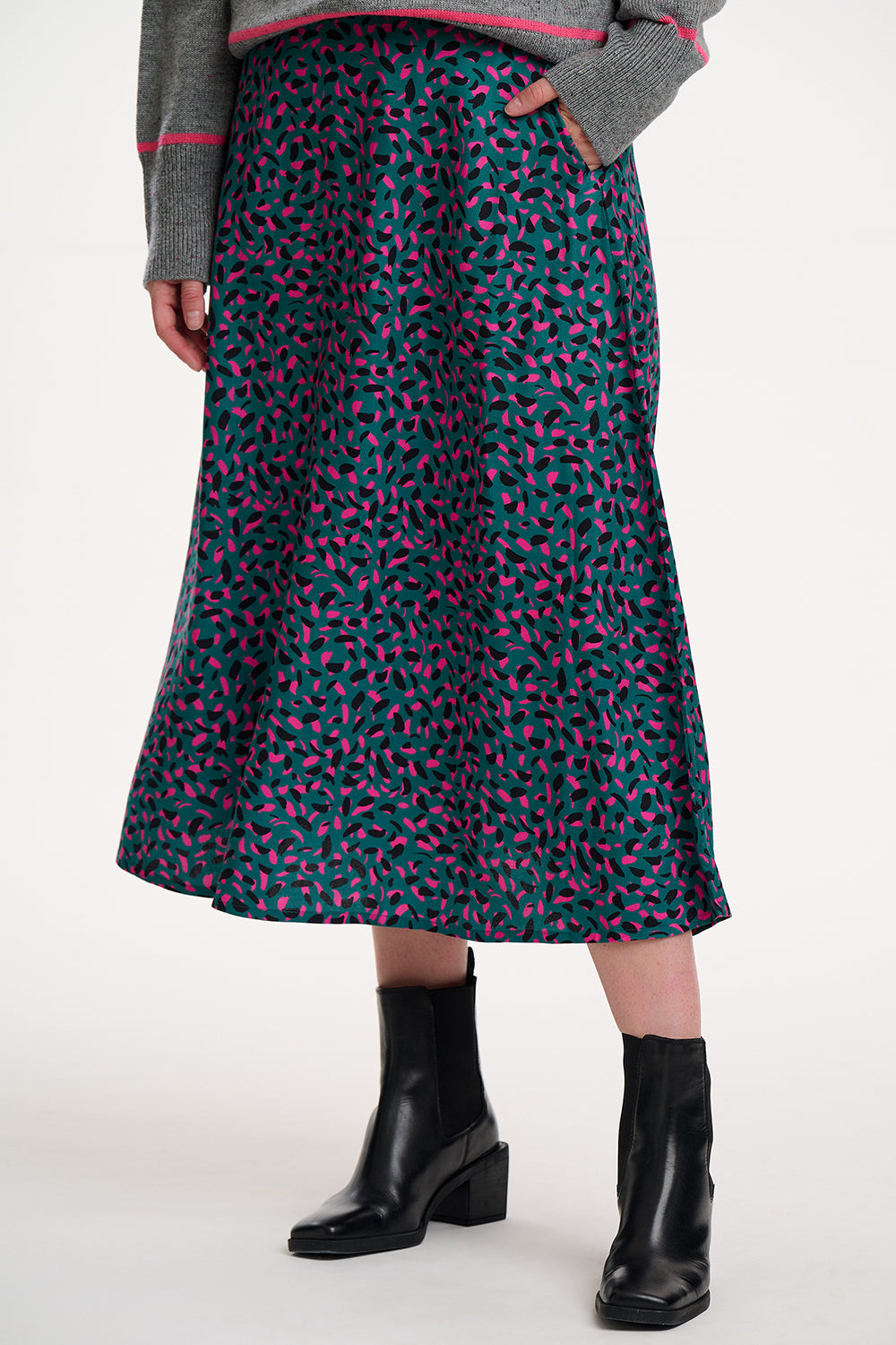 Person wearing a patterned skirt with black boots on a white background