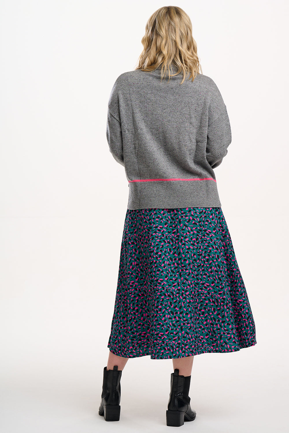 Woman wearing a gray sweater and patterned skirt on a white background